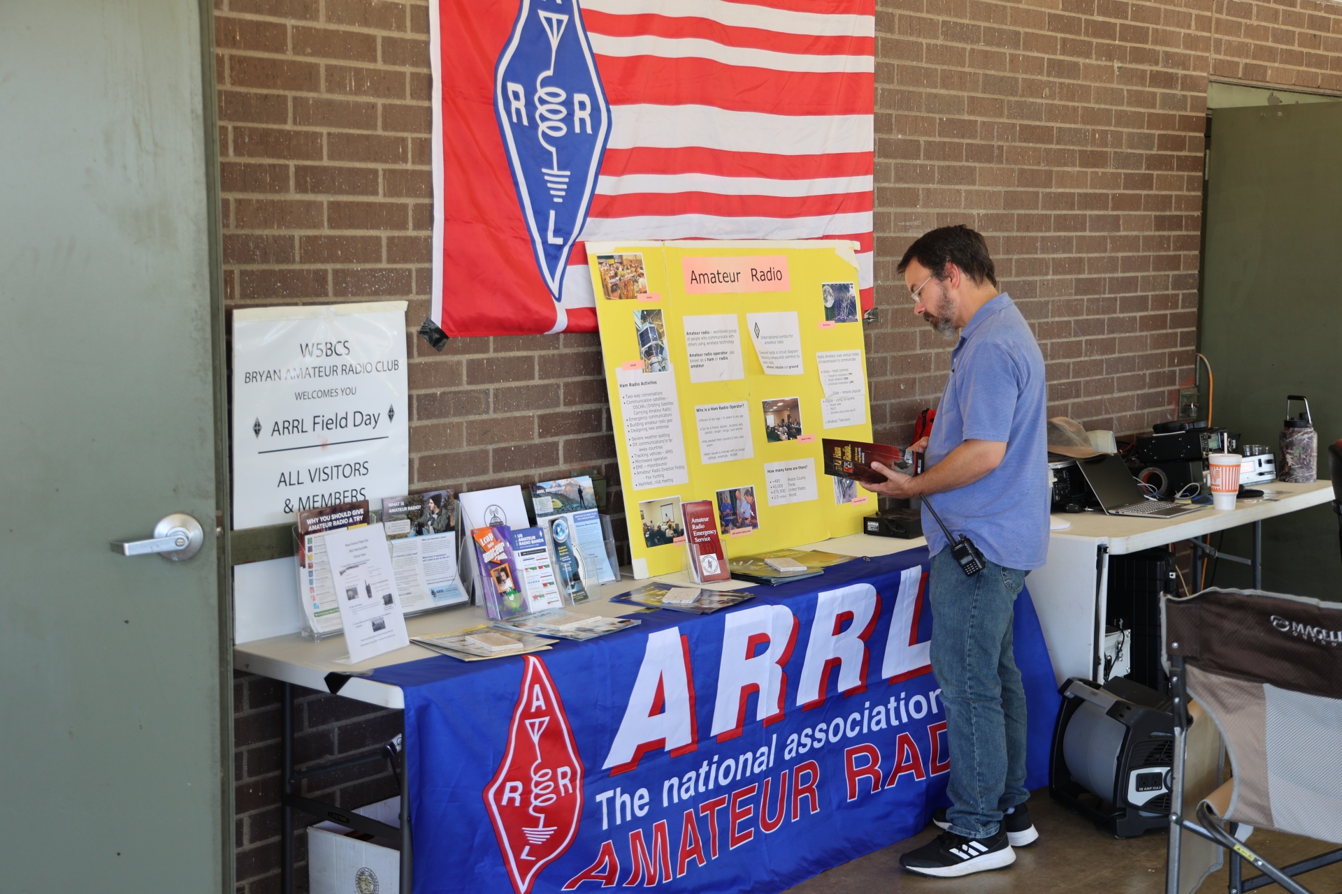 A person reads material about amateur radio at a public information table.