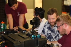 Several people gather around an amateur radio transceiver